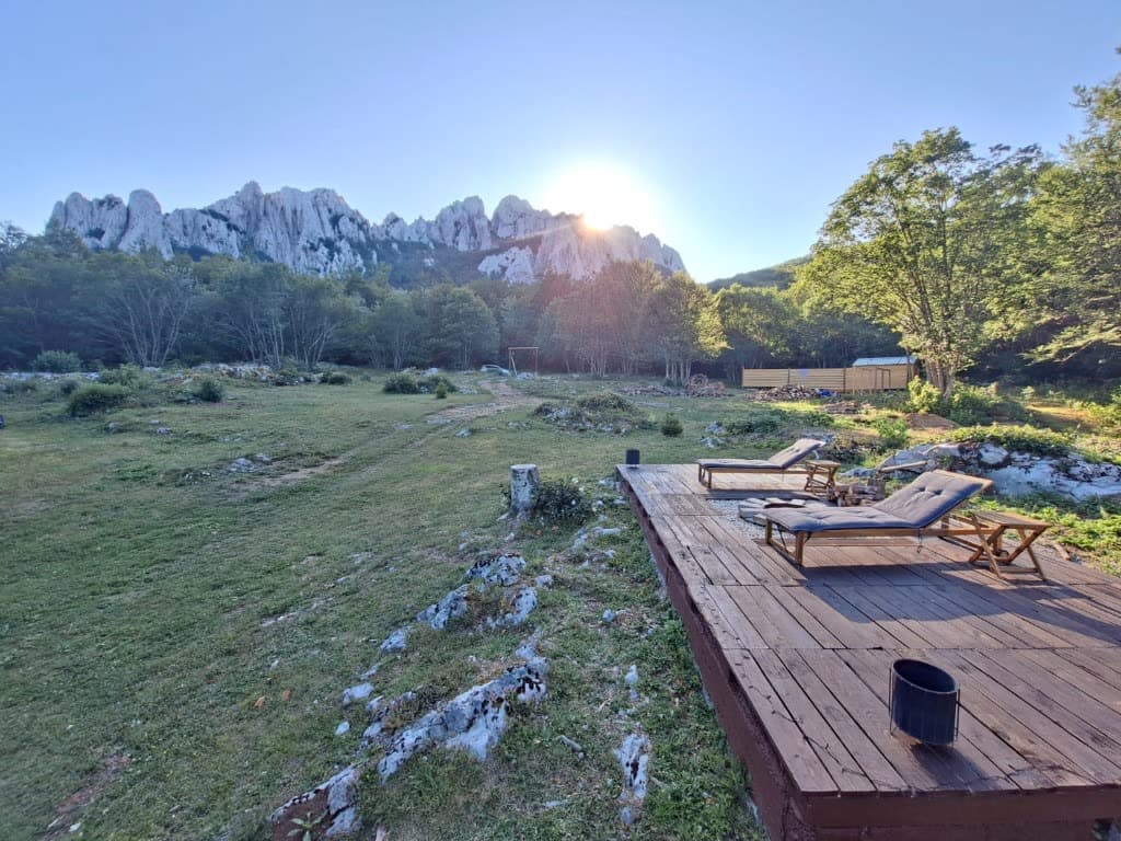 Wooden deck with lounge chairs facing the Velebit peaks at sunset