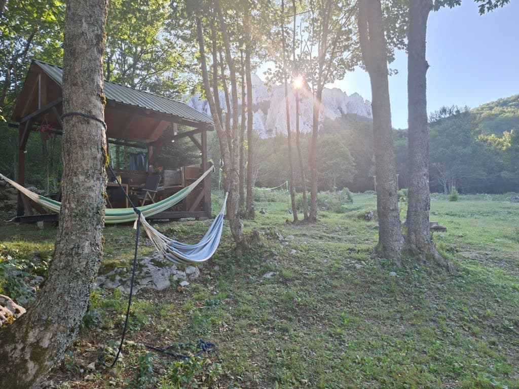 Hammocks in a forest clearing with mountain peaks beyond at Stars Peak